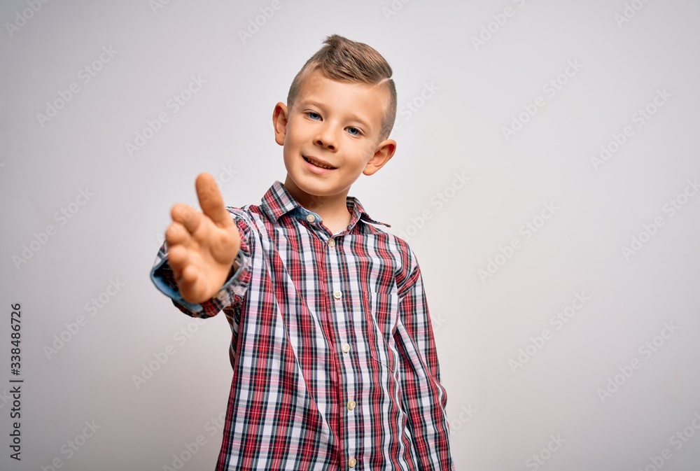 Young little caucasian kid with blue eyes wearing elegant shirt standing over isolated background smiling friendly offering handshake as greeting and welcoming. Successful business. Young little caucasian kid with blue eyes wearing elegant shirt standing over isolated background smiling friendly offering handshake as greeting and welcoming. Successful business.