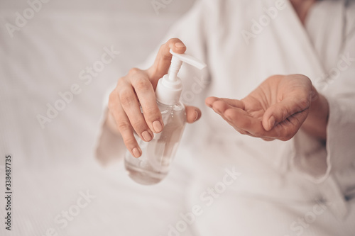 Hand sanitizer woman applying sanitizing alcohol gel liquid rubbing female hands clean personal hygiene coronavirus pervention at home. Sanitiser bottle. Stop COVID19 concept photo