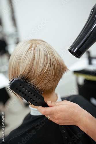 Hairdresser makes hair styling with a hairdryer. Close-up on tools