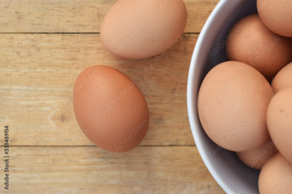 Brown chicken eggs in a white bowl on wooden table soft focus. Brown chicken eggs in a white bowl on wooden table soft focus.