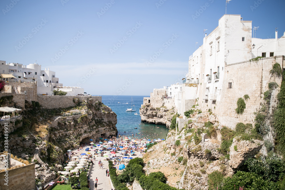 Beautiful beach with people in Polignano a Mare in the southern part of Italy crystal clear azure water