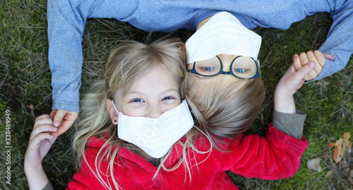 Canvas Print girl and boy lie on the grass in a facial mask during the coronavirus pandemic