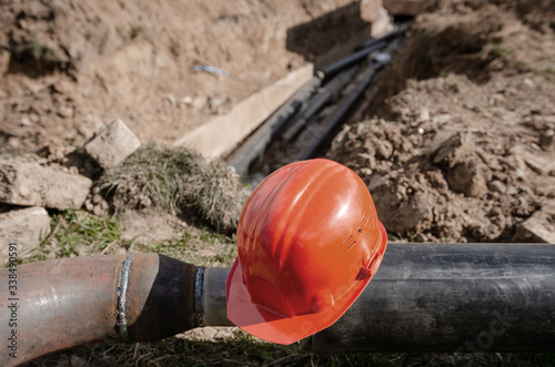 Laying heating pipes in a trench at construction site. Cold and hot water, heating and heating system of apartments in the house. safety helmet and reflective vest hanging on the pipe. 