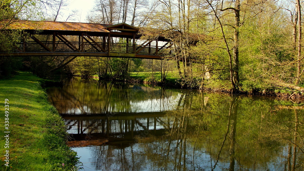 malerische Holzbrücke spiegelt sich im Fluss Nagold zwischen Wiesen und Bäumen im Nagoldtal
