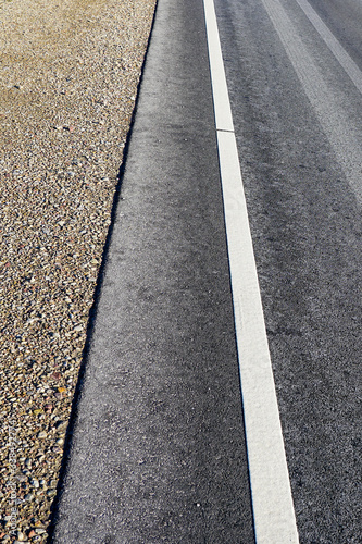 asphalt road with a gravel strip and a white roadside line