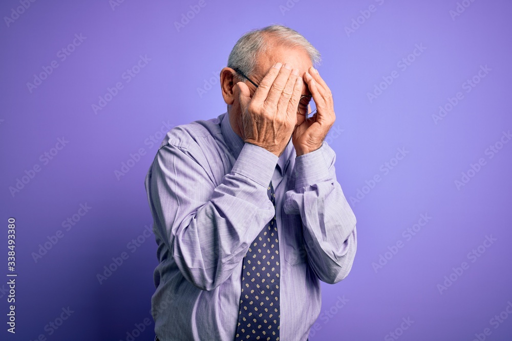 Grey haired senior business man wearing glasses standing over purple isolated background with sad expression covering face with hands while crying. Depression concept. Grey haired senior business man wearing glasses standing over purple isolated background with sad expression covering face with hands while crying. Depression concept.