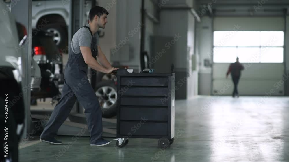 A young automaker pushes a box of tools in the workshop. A young automaker pushes a box of tools in the workshop.