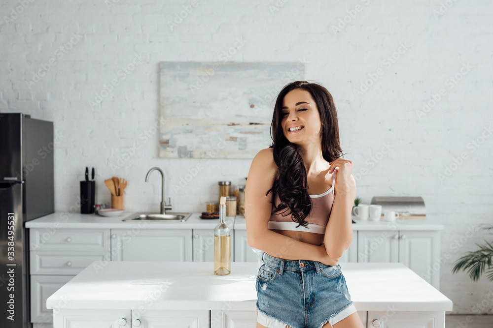 Woman with closed eyes smiling near table in kitchen Woman with closed eyes smiling near table in kitchen