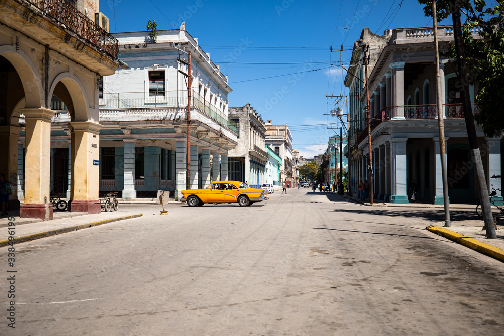 Street in Old Havana with yellow vintage car passing by. 