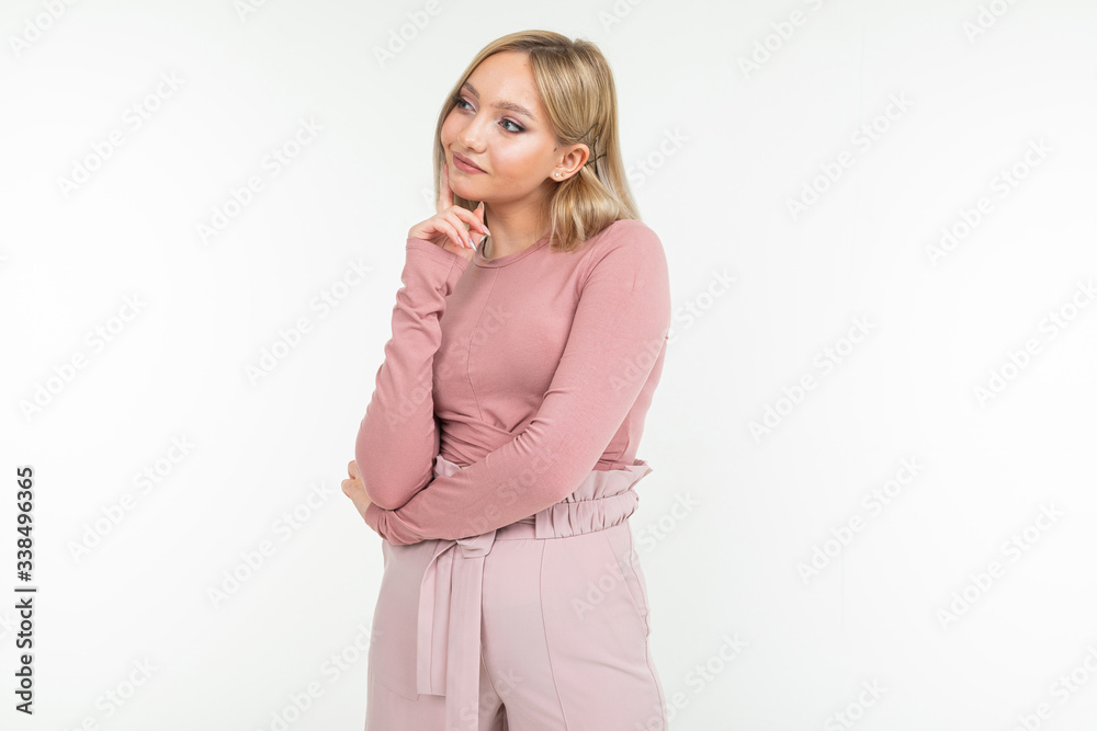 stylish lady in a pink blouse and trousers flirts and thinks on a white studio background stylish lady in a pink blouse and trousers flirts and thinks on a white studio background