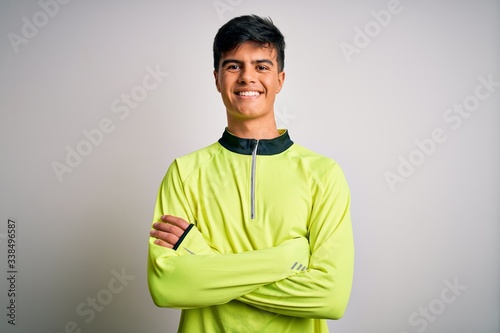 Young handsome sportsman doing sport wearing sportswear over isolated white background happy face smiling with crossed arms looking at the camera. Positive person.