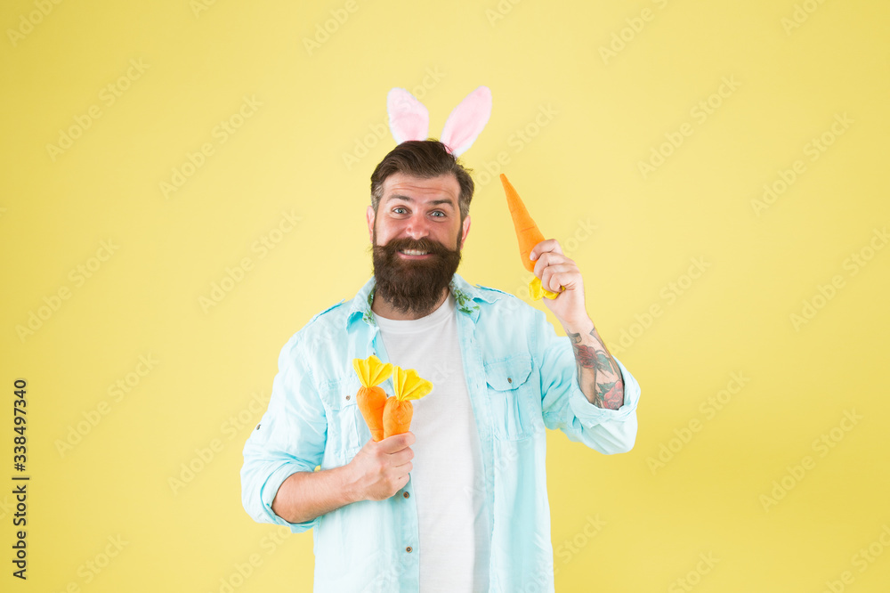 Naklejka premium Eat organic to be healthy. Happy bunny hold organic carrots. Bearded man wear rabbit ears. Organic food for health. Healthy eating habit. Spring avitaminose. Organic and natural