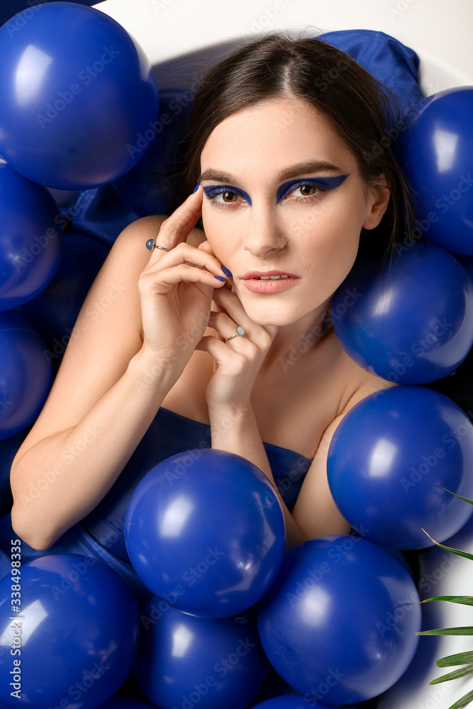 Portrait of fashionable young woman with air balloons lying in bathtub Portrait of fashionable young woman with air balloons lying in bathtub
