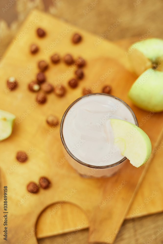 Yogurt with apple and nuts on a wooden background. Daylight.