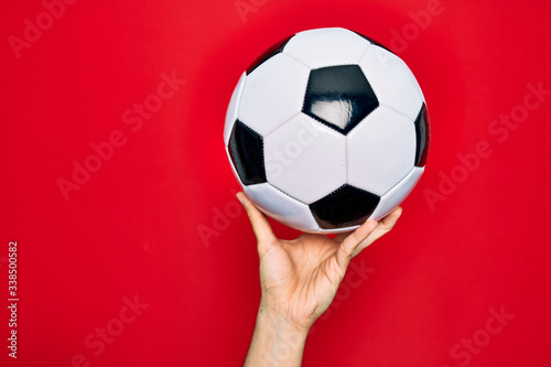 Beautiful hand of man holding football ball over isolated red background