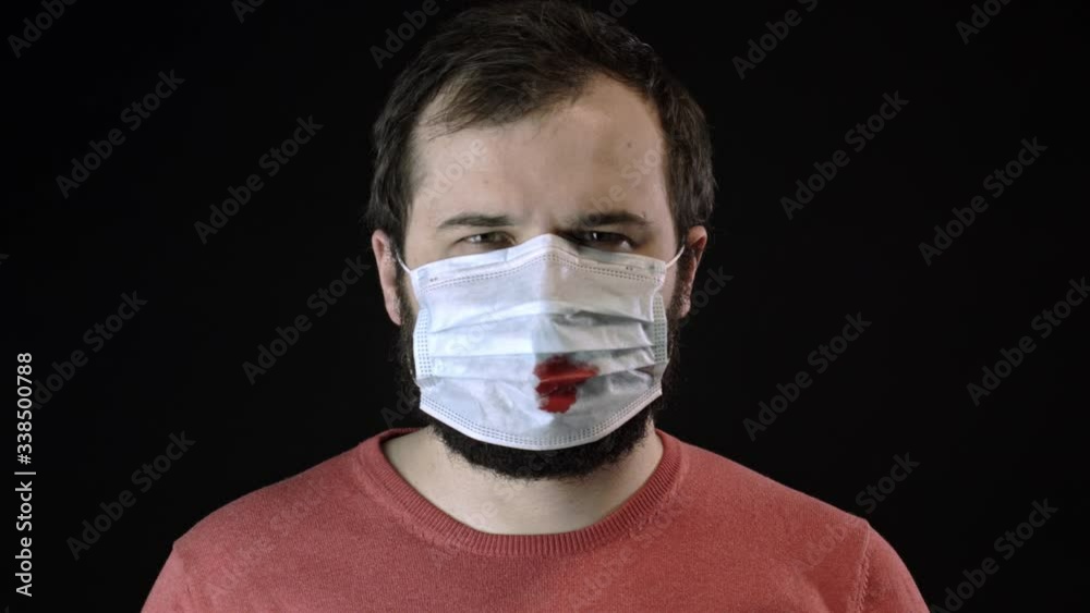 Sick man removes face mask under remains one more with blood on it. Coronavirus Sick man removes face mask under remains one more with blood on it. Coronavirus