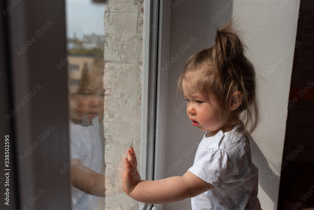 little girl looks out the window and asks outside during quarantine caused by coronavirus. little girl looks out the window and asks outside during quarantine caused by coronavirus.