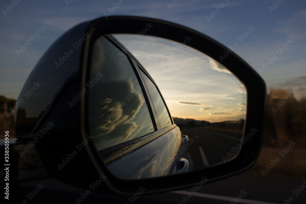 Car's rear mirror at sunset