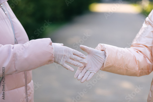 Shaking hands in medical gloves in front of a green background. Healthcare concept