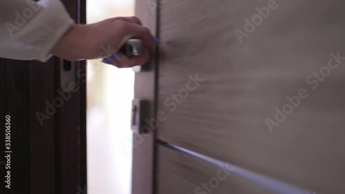 Young woman opens the door and enters the room. Close-up female hand opens and closes the door