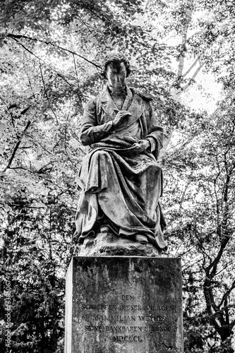 Statue of Maximilian Weyhe (1850) in Reitallee park under gree tree branches in Dusseldorf, North Rhine Westphalia, Germany
