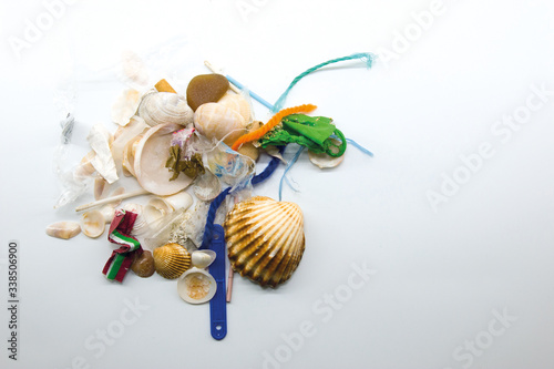 Sea shells mixed with plastic waste. Climate change and ocean pollution concept.