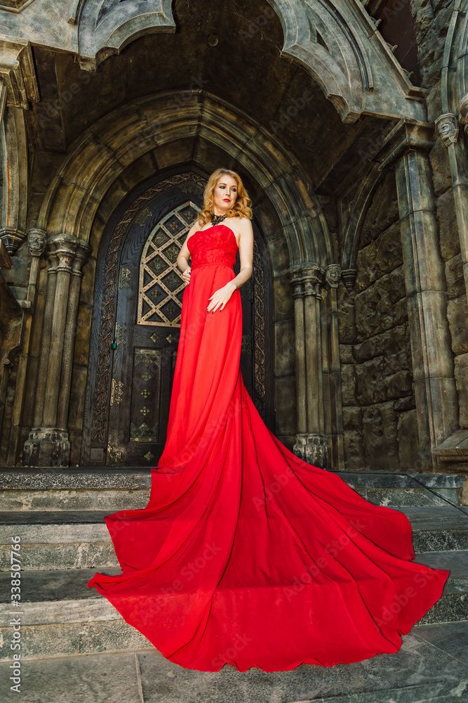 A woman in a red dress stands on a background of a medieval castle A woman in a red dress stands on a background of a medieval castle