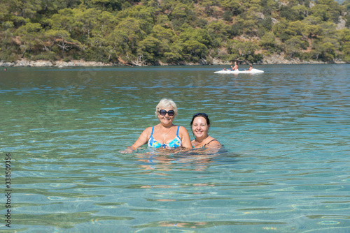 Women are posing in shallow water of Oludeniz beach, Turkey.