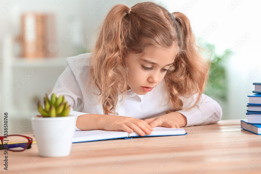 Cute little schoolgirl doing task at desk in classroom Cute little schoolgirl doing task at desk in classroom