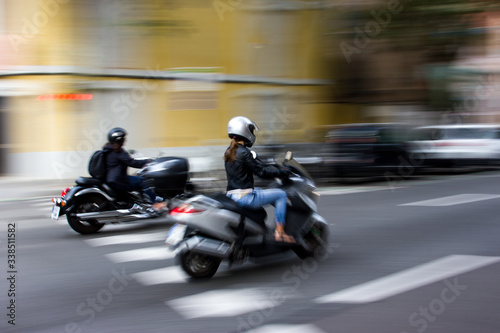 Woman driving a motorcycle in a city street. © Andy Left