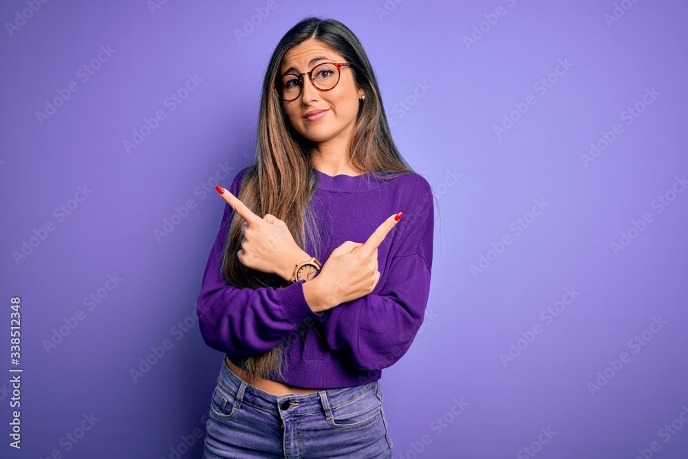 Young beautiful smart woman wearing glasses over purple isolated background Pointing to both sides with fingers, different direction disagree Young beautiful smart woman wearing glasses over purple isolated background Pointing to both sides with fingers, different direction disagree