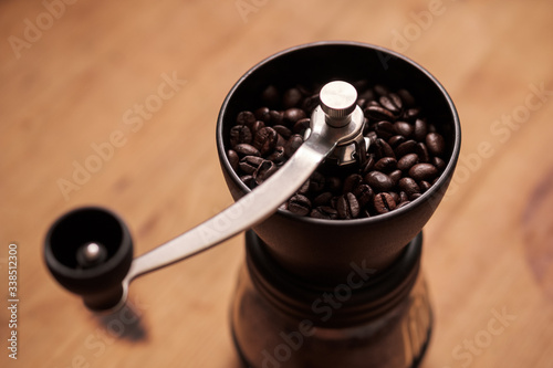 Fototapeta Naklejka Na Ścianę i Meble -  Close-up view of a manual Coffee Grinder filled with whole coffee beans.