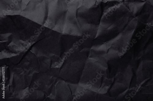 Black crumpled paper texture as background. Copy space text