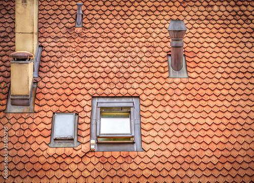 Red tiled roof with chimneys and a small window