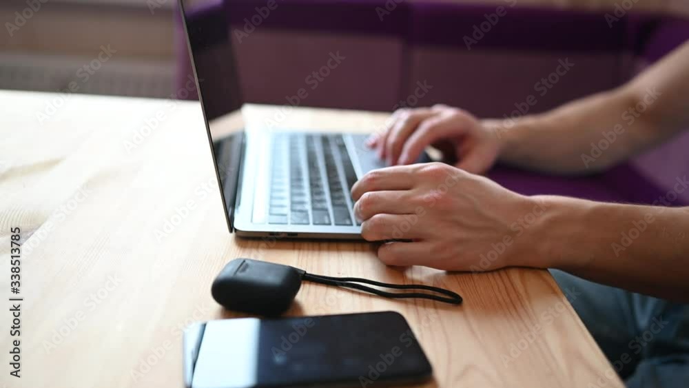 Unrecognizable man hands with smartphone and headphones working on a laptop during coronavirus isolation home quarantine. Covid-19 pandemic Corona virus. Distance online work from home concept. Unrecognizable man hands with smartphone and headphones working on a laptop during coronavirus isolation home quarantine. Covid-19 pandemic Corona virus. Distance online work from home concept.