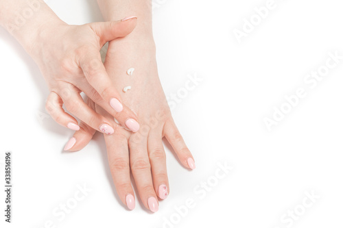 The women distributes moisturizing cream on her hands. Hands on a white background with a jar of white cream.
