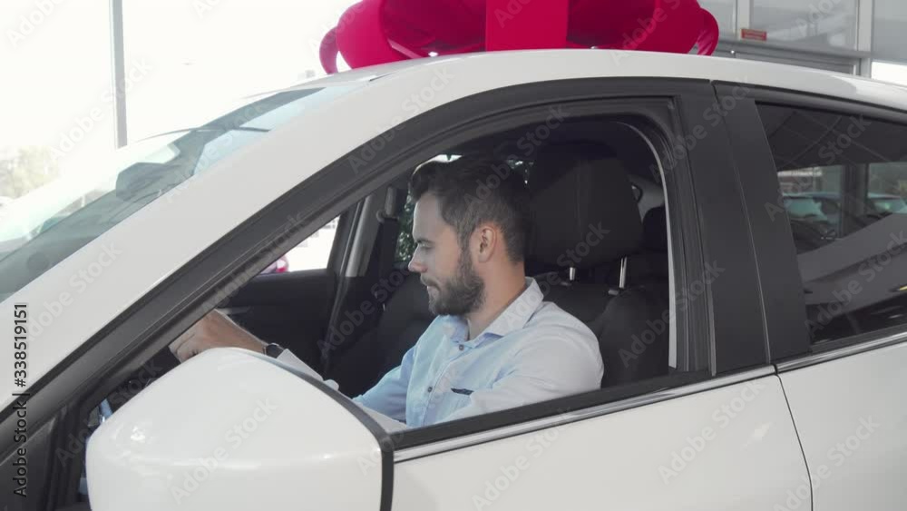 Handsome cheerful man showing car keys to the camera sitting in his new auto. Attractive male driver celebrating buying new automobile at car dealership Handsome cheerful man showing car keys to the camera sitting in his new auto. Attractive male driver celebrating buying new automobile at car dealership