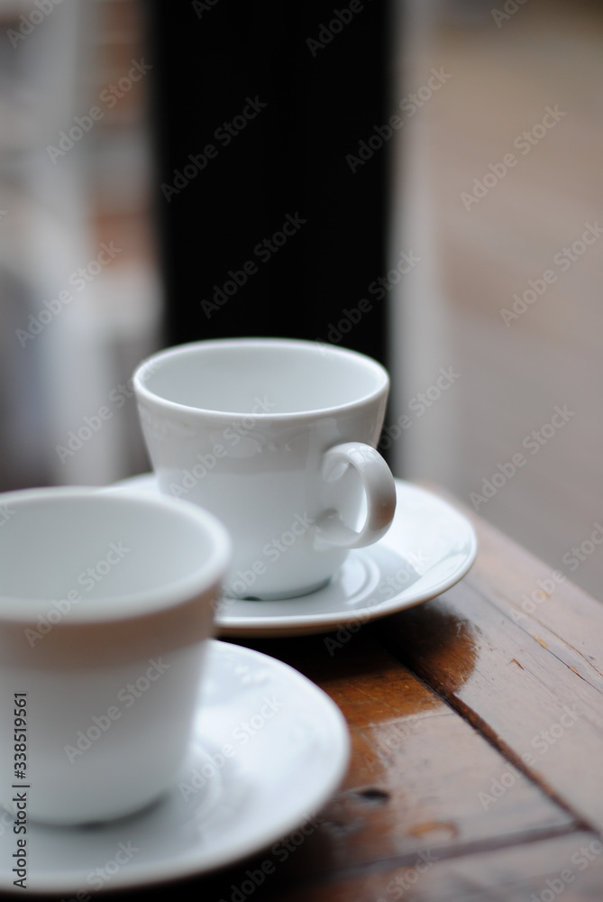 Dos tazas de café de color blanco encima de una mesa de madera.