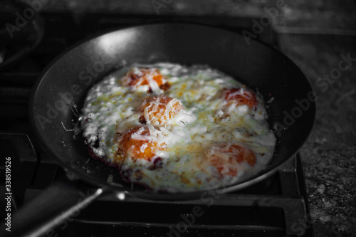 Fried eggs sprinkled with cheese lie in a hot pan