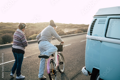 Old modern senior couple viewed from back enjoy the outdoor leisure activity together - bike and van for transport concept - sun  and sunlight in background photo