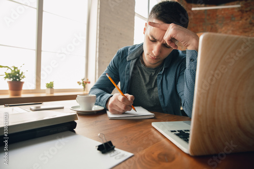 Creative workplace - organized work space as you like for inspiration. Man working in office in comfortable attire, relaxed position and messy table. Choose atmosphere you want - ideal clear or chaos.