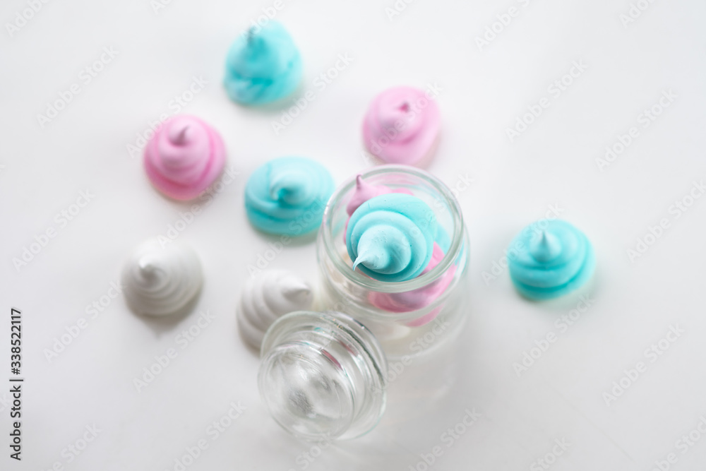 Colorful tasty meringues cookies in glass jars on white table background Colorful tasty meringues cookies in glass jars on white table background