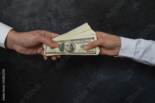 Businessman give dollars another businessman at the black background.