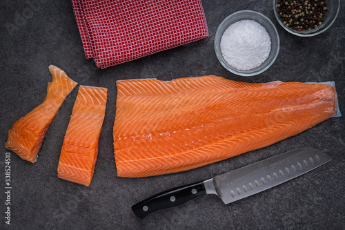Foto Salmon filets being cut with a Santoku Knife,  salt and pepper and kitchen towel
