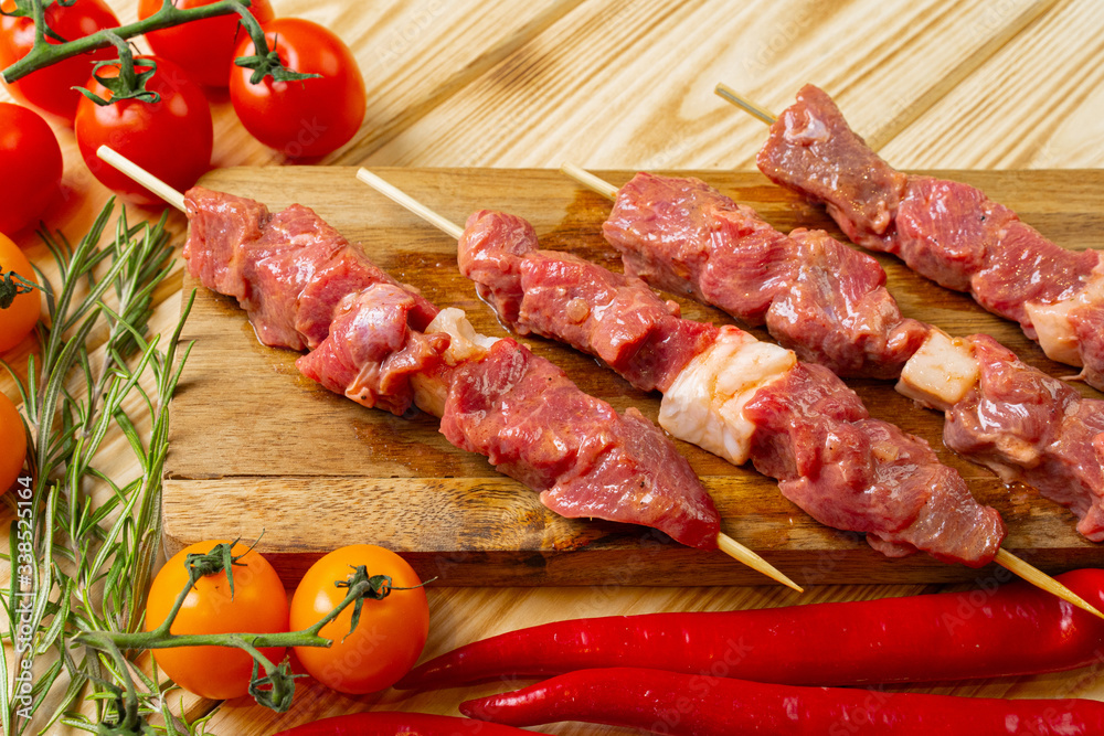 Raw kebab from meat on a wooden background with vegetables. Raw kebab from meat on a wooden background with vegetables.