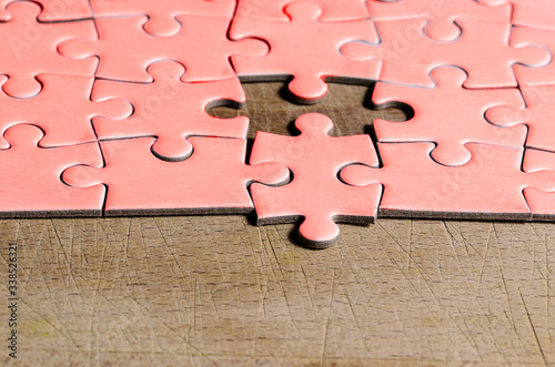 the unexpected solution.
pink jigsaw/puzzle with one piece at wrong position, on a wooden table background, symbol of problem solving and new vision