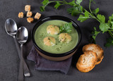 Cream-soup greens with croutons in a bowl on a dark background top view