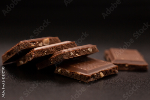 Chocolate with nuts. Chunks of chocolate with nuts on a dark background.