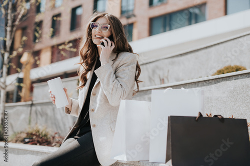 Photos Attractive cute girl with the shopping bags and smarphone in her hand