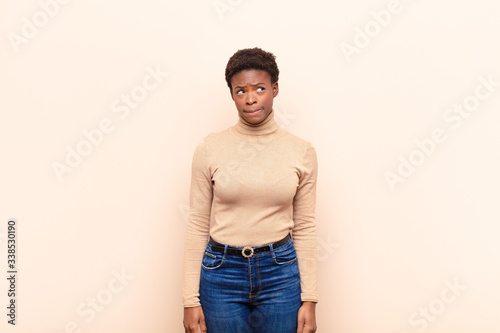 young pretty black womanlooking puzzled and confused, wondering or trying to solve a problem or thinking photo